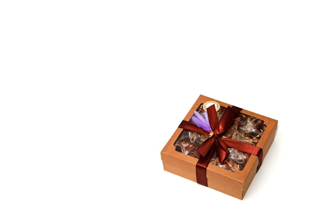 Confezione regalo con noci su sfondo bianco isolante per le vacanze. Regali Confezionati in scatola decorata con nastro marrone e piume viola. Regali per Natale, anniversario, compleanno. Copia spazio