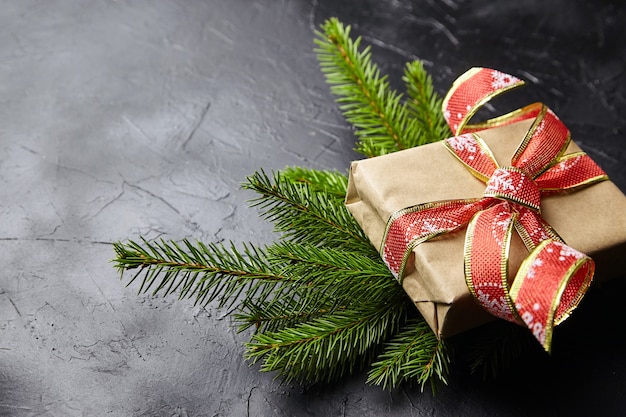 Confezione regalo con ramo di albero di Natale verde su sfondo scuro