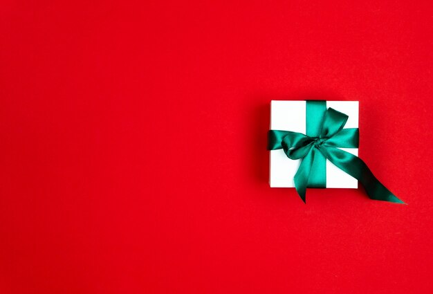 Confezione regalo con un nastro di raso verde su sfondo rosso Concetto di Natale e Capodanno Copia spazio