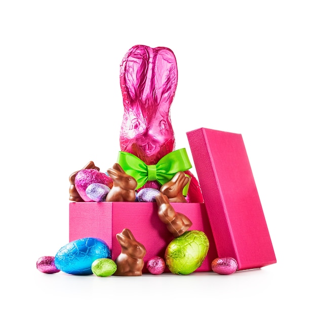 Confezione regalo con uova di pasqua di cioccolato coniglio con fiocco avvolto in un coniglietto in lamina rosa e caramelle colorate