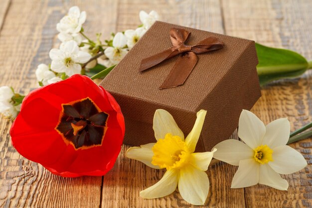 Confezione regalo decorata con fiori di tulipani narcisi e gelsomino su tavole di legno