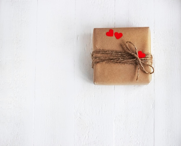 Confezione regalo di carta artigianale con cuori sullo sfondo di legno bianco San Valentino