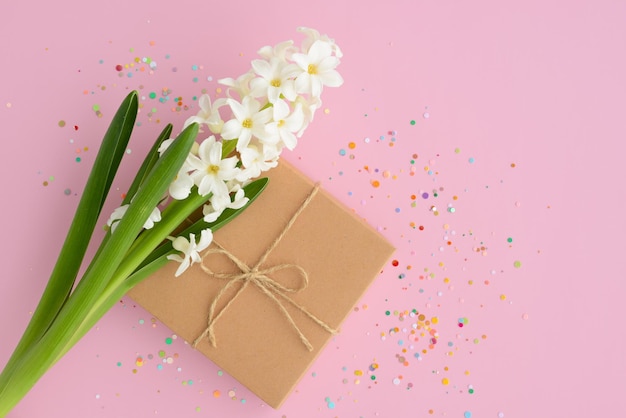 Confezione regalo di fiori primaverili bianchi confetti su sfondo rosa Carta floreale per la festa della mamma della festa della donna