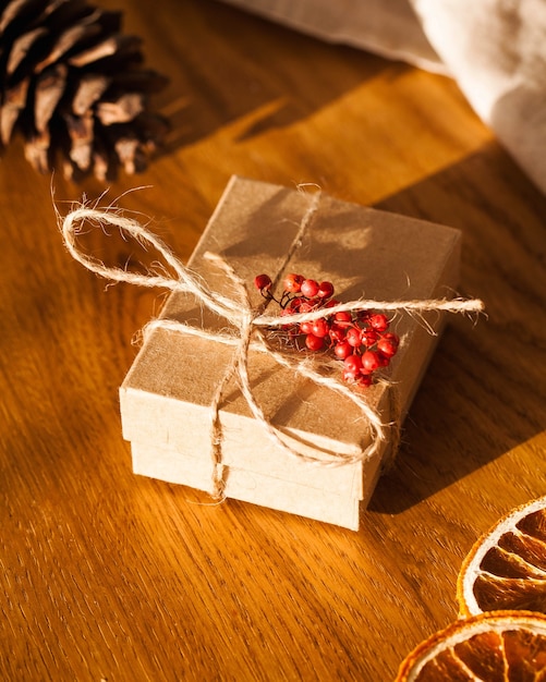 Confezione regalo di Natale artigianale su un tavolo di legno circondato da coni e arance essiccate. Un regalo con le tue mani. Copiare lo spazio Foto di alta qualità