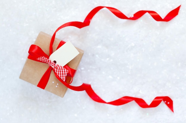 Confezione regalo di Natale con nastro rosso e tag vuoto per il testo sulla neve