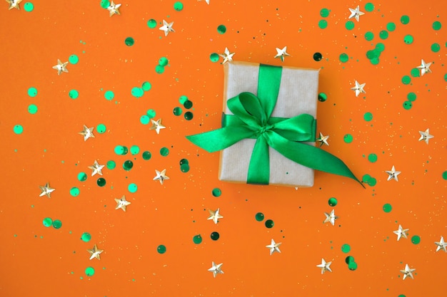 Confezione regalo di Natale con nastro verde di colore di sfondo con coriandoli lucidi