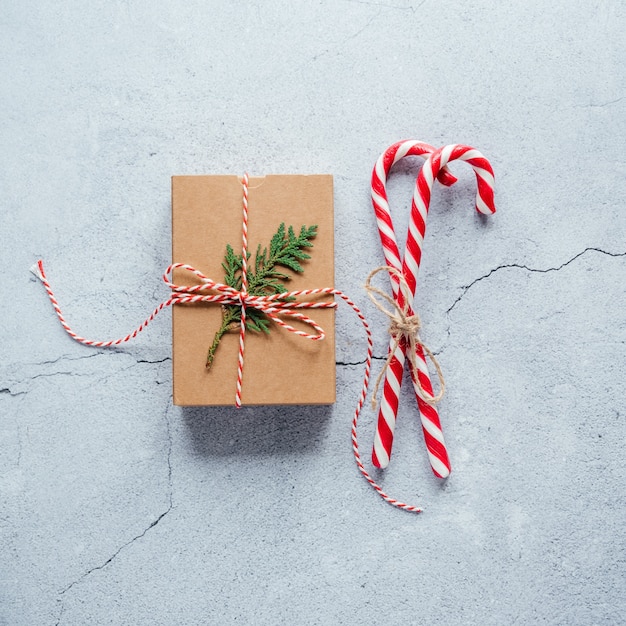 Confezione regalo di Natale decorata con un ramo di tuia e bastoncini di zucchero