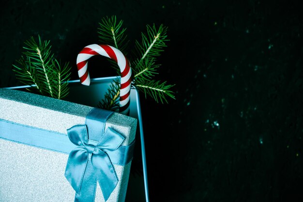 Confezione regalo di Natale legata con nastro blu con fiocco con albero di Natale verde e caramello su sfondo scuro