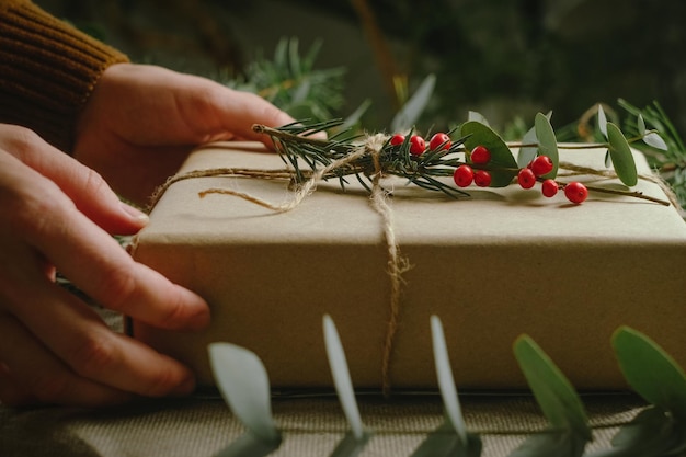 Confezione regalo di Natale sostenibile Mani che avvolgono la confezione regalo per Natale