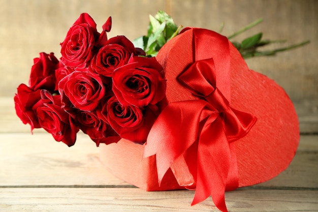 Confezione regalo di San Valentino a forma di cuore con rose rosse sul vecchio tavolo di legno