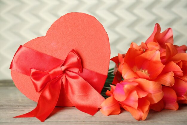 Confezione regalo di San Valentino a forma di cuore con tulipani su tavola di legno