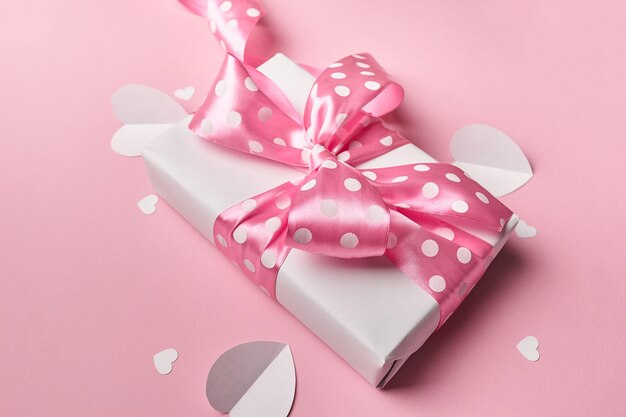 Confezione regalo di San Valentino con cuori di carta su sfondo rosa