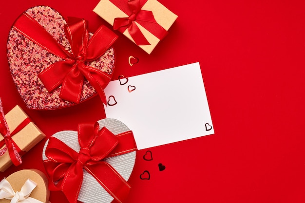 Confezione regalo di varie scelte a forma di cuore con un nastro rosso su sfondo rosso. Cartolina del concetto di San Valentino. Vista dall'alto piatta con spazio di copia.