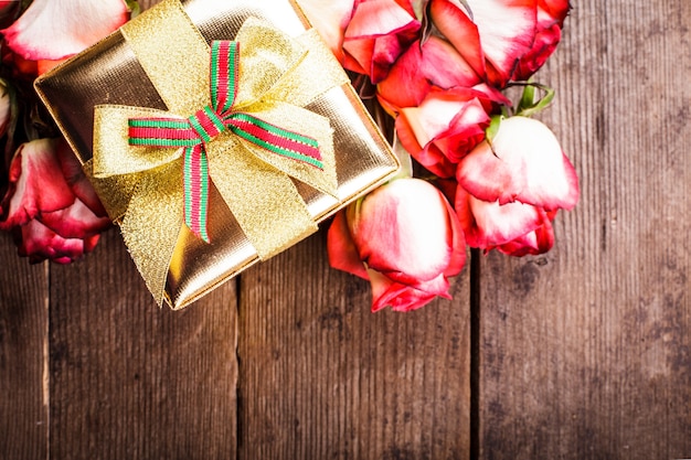 Confezione regalo dorata e bouquet di rose sul tavolo
