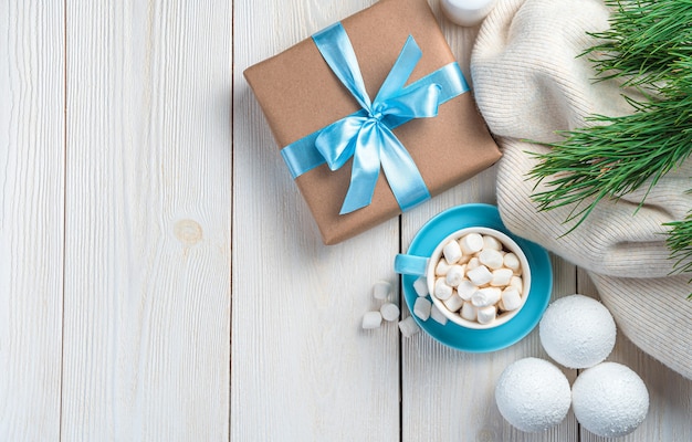 Confezione regalo e caffè con marshmallow su sfondo chiaro con rami di pino