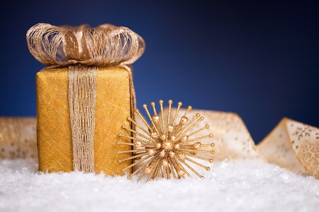 Confezione regalo e decorazioni per l'albero di Natale nella neve su sfondo blu