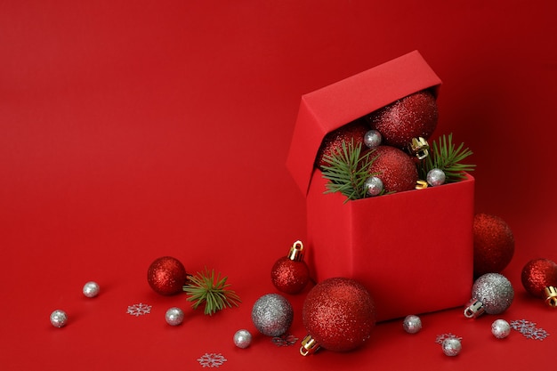 Confezione regalo e palline di Natale su sfondo rosso