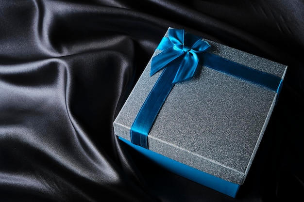 Confezione regalo in argento con tessuto di seta nero sfondo fiocco blu