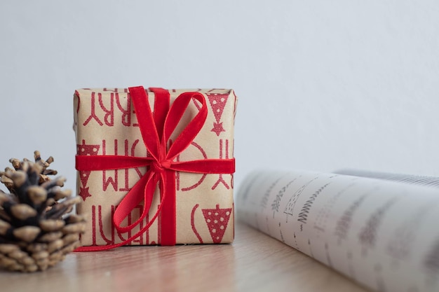 Confezione regalo in carta da regalo artigianale e nastro rosso su tavola di legno