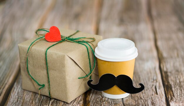 Confezione regalo in carta kraft bicchiere di carta con caffè Su uno sfondo di legno Concetto regalo per uomini