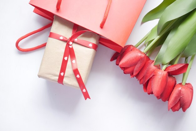Confezione regalo in un sacchetto della spesa e fiore di tulipano rosso sul tavolo