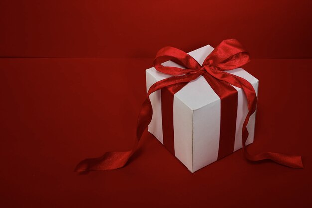 Confezione regalo Natale con nastro rosso su sfondo rosso