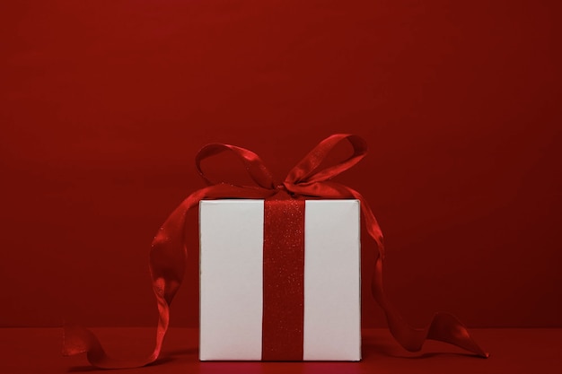 Confezione regalo Natale con nastro rosso su sfondo rosso