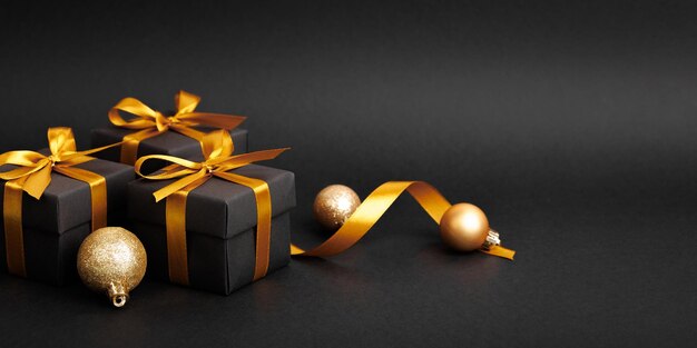 Confezione regalo nera con fiocco in nastro dorato su sfondo nero