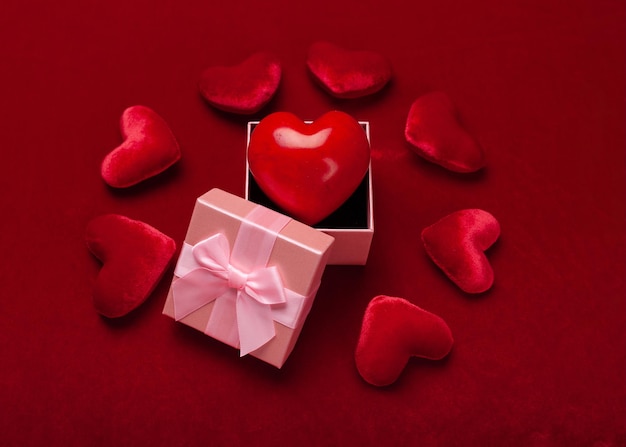 Confezione regalo o regalo con fiocco rosso e cuore glitterato su sfondo rosso per San Valentino