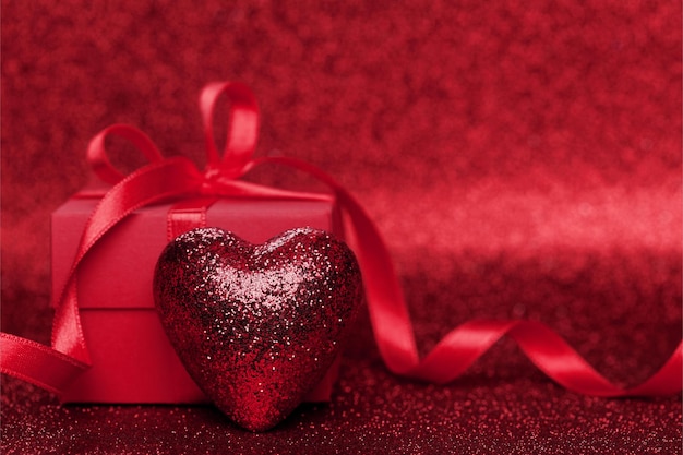 Confezione regalo o regalo con fiocco rosso e cuore su sfondo scintillante per San Valentino