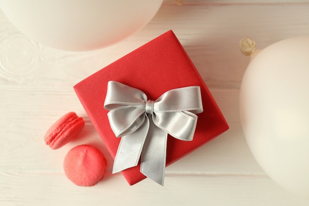 Confezione regalo, palloncini e amaretti sul tavolo di legno bianco