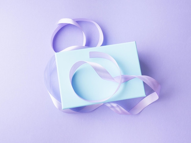 Confezione regalo pastello blu con nastro su sfondo viola