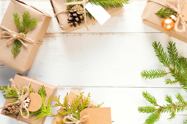 Confezione regalo per Natale e Capodanno in materiali ecologici: carta kraft, rami di abete vivo, pigne, spago. Etichette con mock up, decoro naturale, fatte a mano, fai da te. Piatto, sfondo, cornice, minimalismo