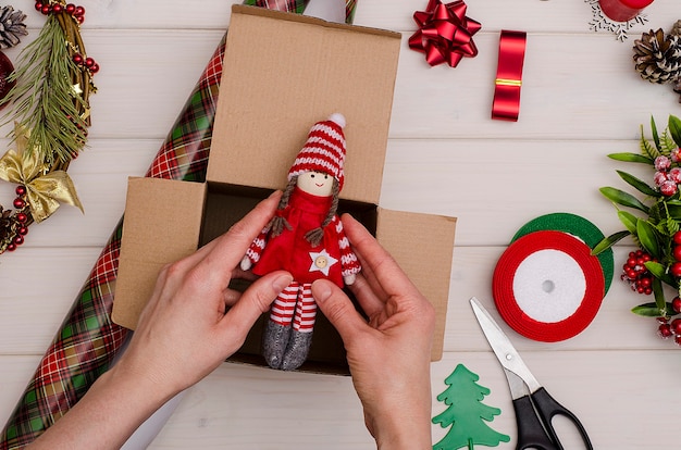 Confezione regalo per Natale e Capodanno su uno sfondo di legno bianco. Bambola giocattolo, regali per bambini. Preparazione per la vacanza.