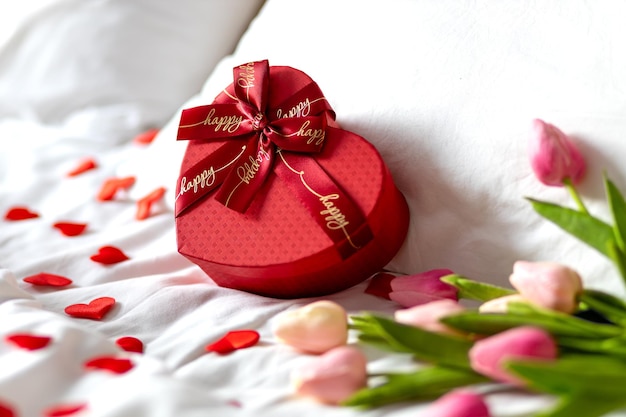 Confezione regalo rossa a forma di cuore sul letto San Valentino