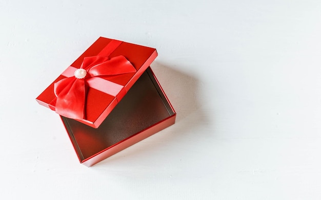 Confezione regalo rossa aperta su tavola di legno bianca