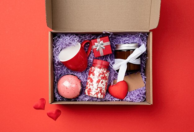 Confezione regalo stagionale per San Valentino con tazza rossa candela e dolci a forma di cuore su sfondo rosso