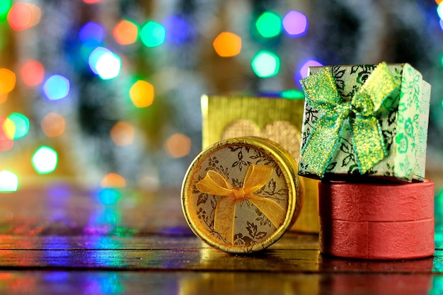 Confezioni regalo sul tavolo di legno, decorazioni natalizie, luci sfocate sullo sfondo