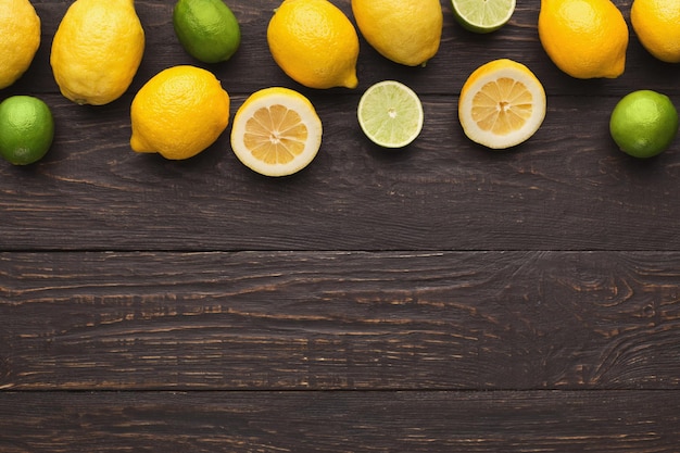 Confine di agrumi assortiti su fondo di legno rustico, spazio di copia. Vista dall'alto su limoni e lime, distesi. Mockup per la ricetta della limonata esotica