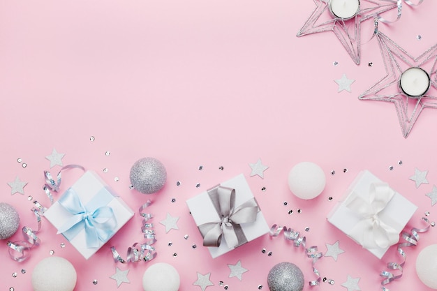 Confine natalizio con scatole regalo palle decorazione e paillettes su tavolo rosa vista superiore Flat lay Co