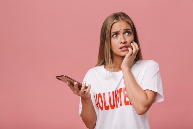 Confusa giovane ragazza volontaria in piedi isolata, usando il telefono cellulare