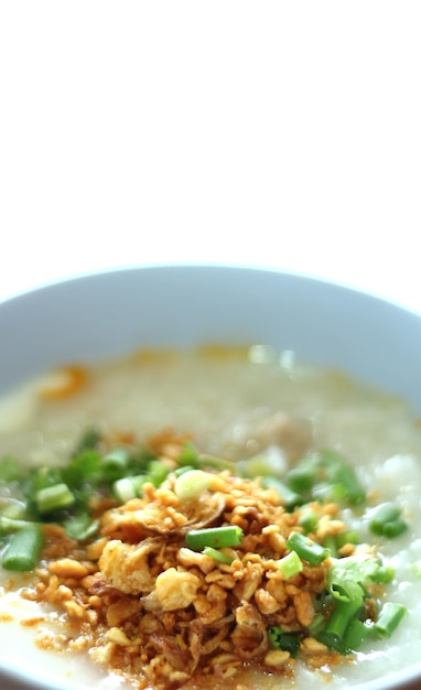 Congee in una ciotola con aglio fritto e cipolla su sfondo bianco