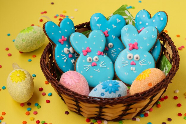 Conigli divertenti di Pasqua, biscotti di panpepato dipinti in casa in smalto su sfondo giallo, vista dall'alto