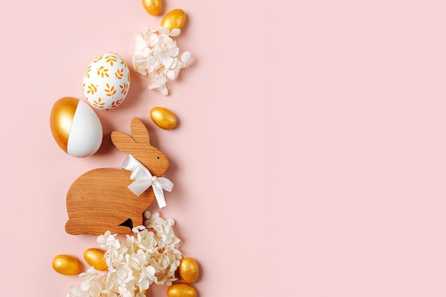 Coniglietto di Pasqua e uova d'oro con caramelle e fiori su sfondo rosa pastello Concetto di vacanza Buona Pasqua cardx9