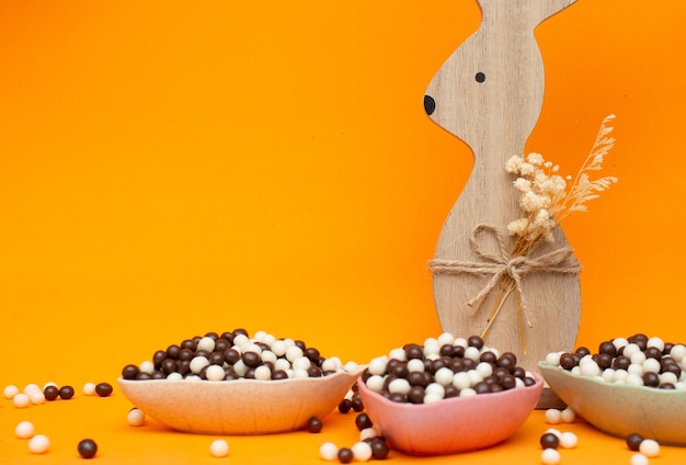 Coniglietto di Pasqua su uno sfondo arancione e piccole palline di cioccolato Pasqua