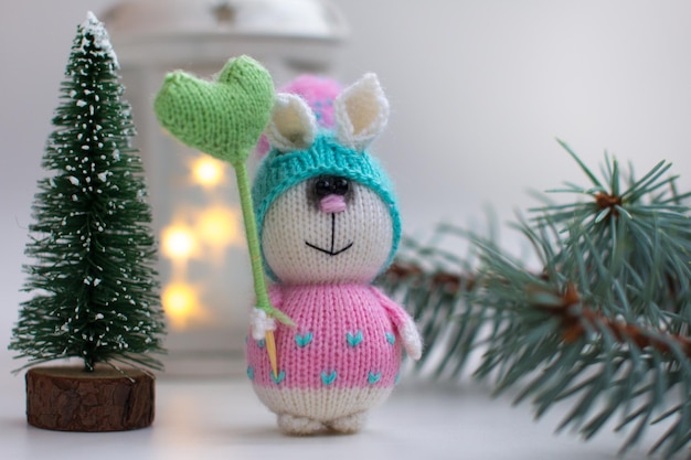 Coniglietto lavorato a maglia con regali su sfondo di legno con albero di Natale Capodanno della lepre 2023 fatto a mano