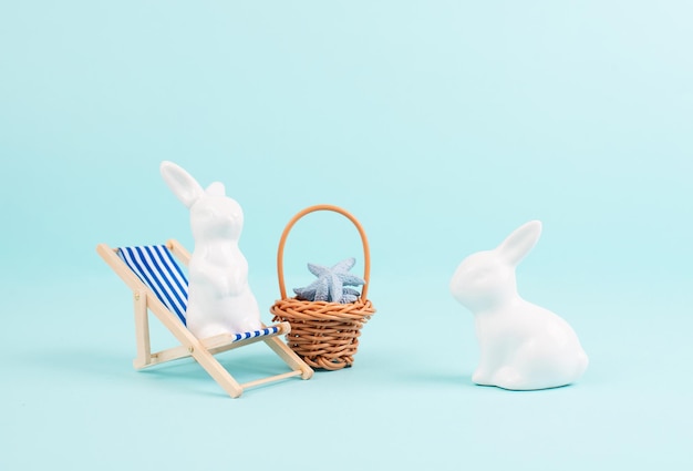 Coniglietto o coniglio seduto sul cestino della sedia a sdraio con stelle marine vacanze di pasqua in riva al mare
