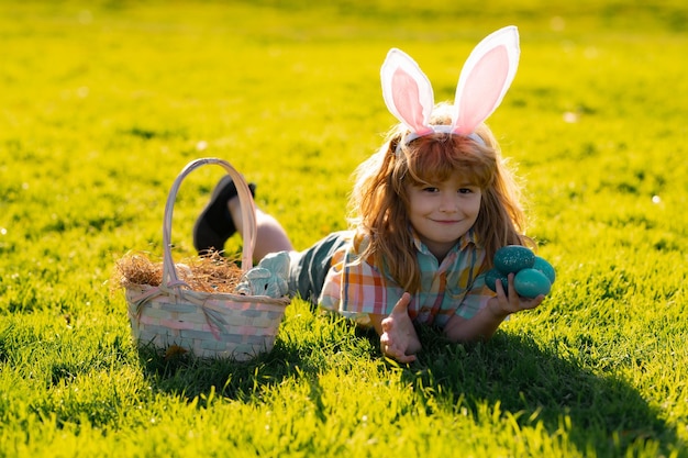 Coniglietto pasquale Bambini Ragazzo con orecchie da coniglio a caccia di uova di Pasqua nel parco all'aperto Vacanze primaverili