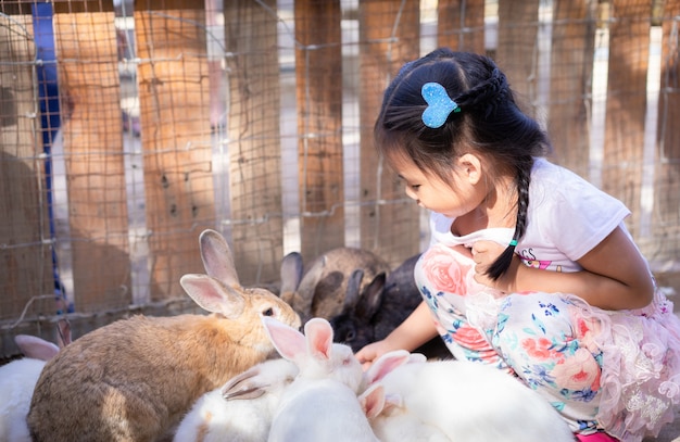 Coniglio d&#39;alimentazione della piccola ragazza asiatica sveglia sull&#39;azienda agricola