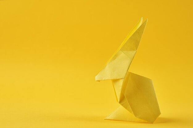 Coniglio Esater origami di carta su una parete gialla. Concetto di celebrazione di Pasqua